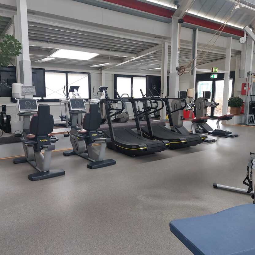 Fitnessstudio mit modernen Laufb&auml;ndern, Ergometern und einem Freihantelbereich in hellem, offenen Raum.