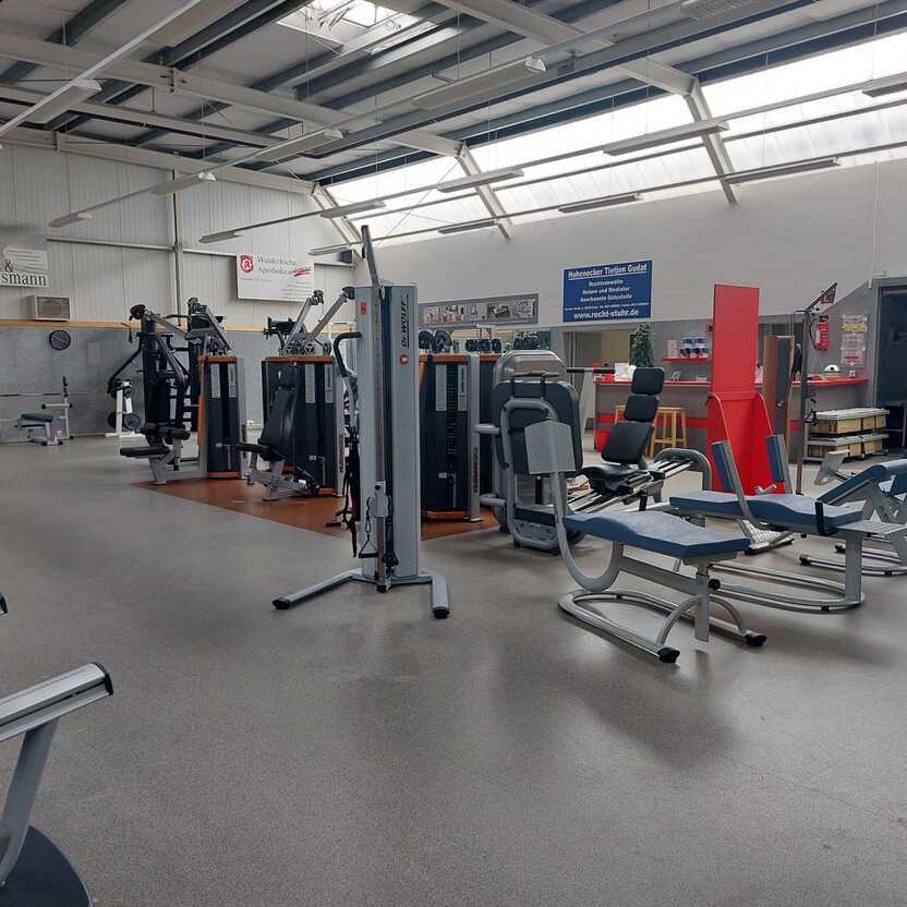 Innenansicht eines Fitnessstudios mit verschiedenen Trainingsger&auml;ten und freien Fl&auml;chen zum Trainieren.